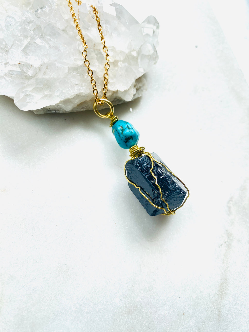 Handmade necklace featuring a small Turquoise stone atop a larger Black Tourmaline stone, on a golden necklace.